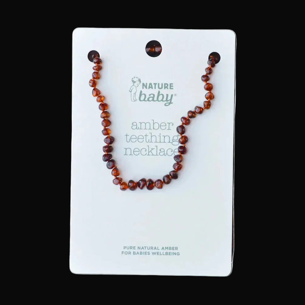 A natural amber beaded teething necklace displayed on a white card labeled 'Nature baby amber teething necklace,' placed on a rustic dark wood surface.